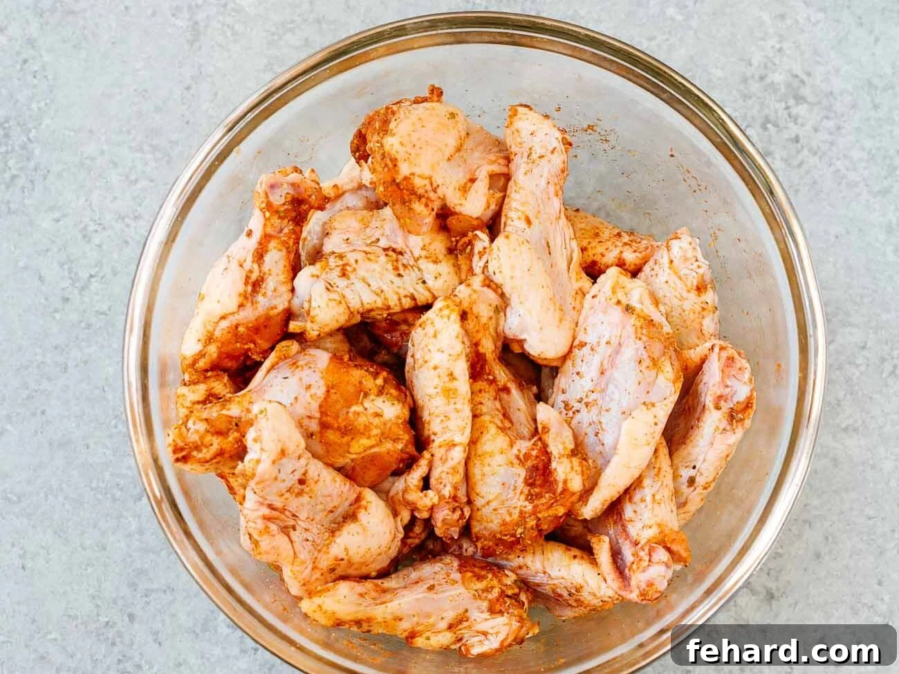seasoned chicken wings in a glass bowl 
