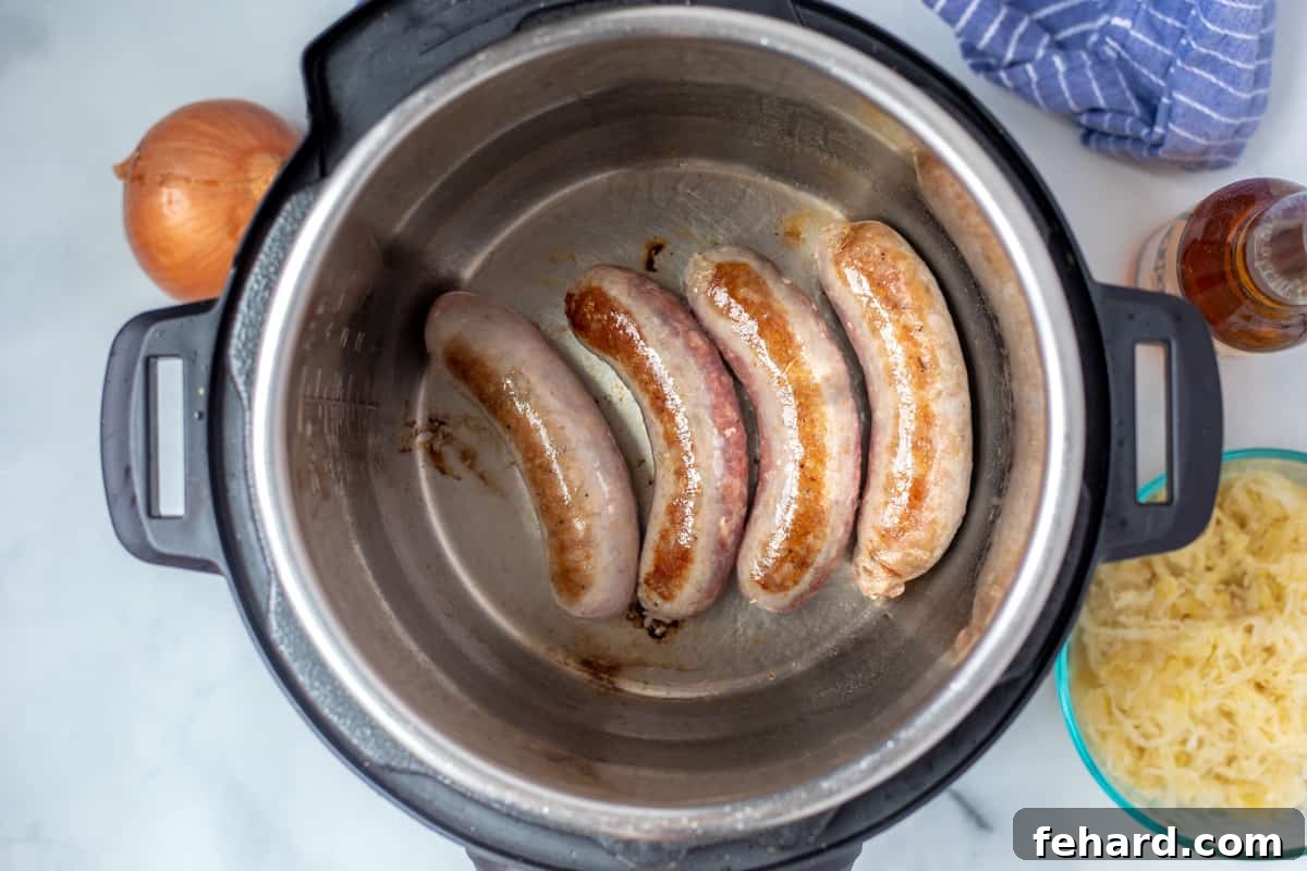 Golden-browned brats inside the inner pot of an Instant Pot, after searing. 