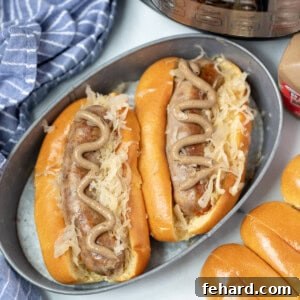 Two bratwurst in buns with sauerkraut and mustard next to instant pot.
