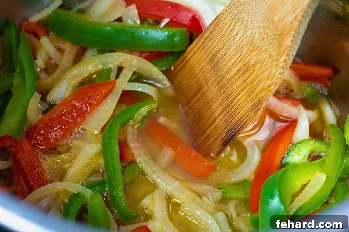Wooden spoon deglazing inner pot after sauteing peppers and onions in inner pot.