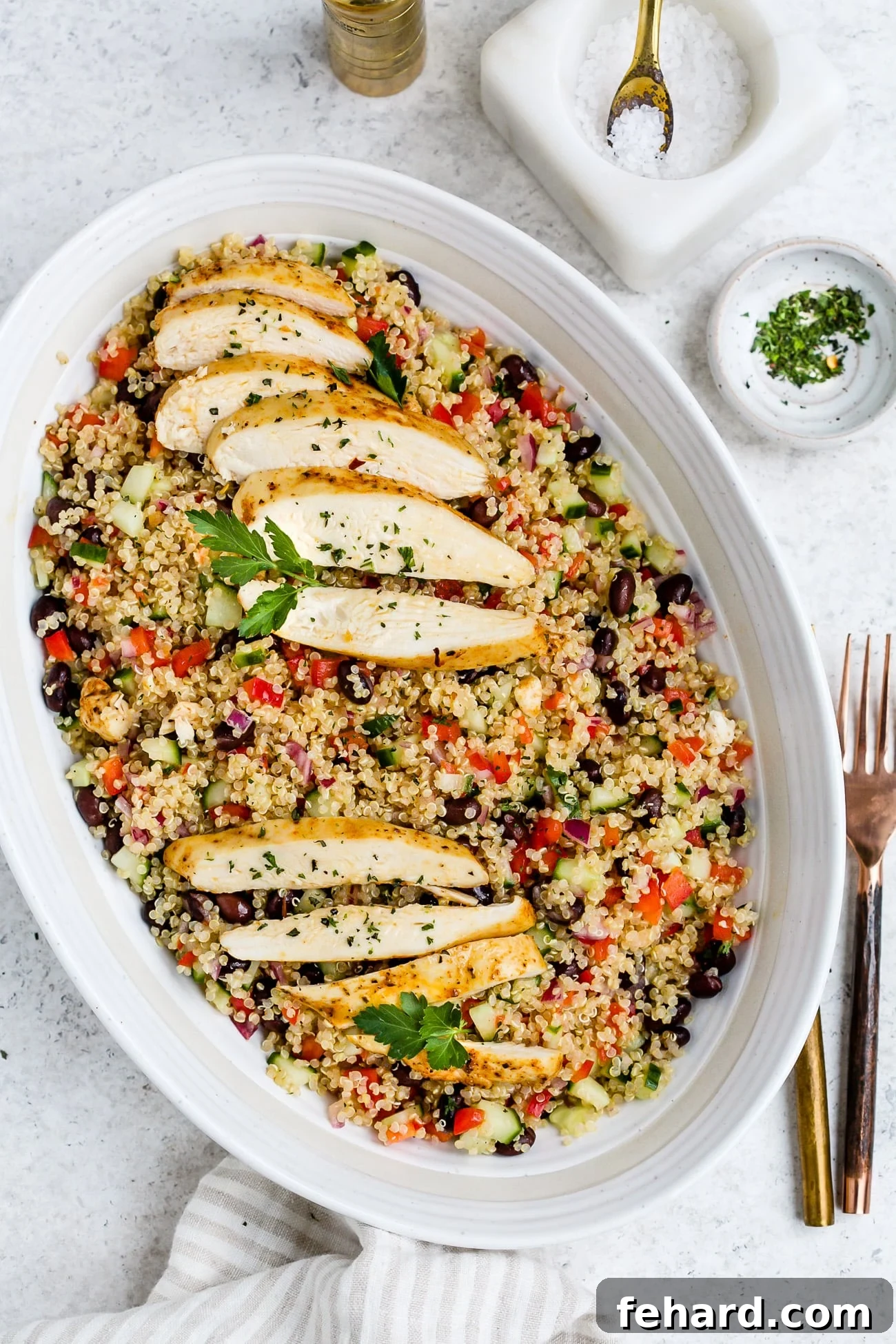 Chicken quinoa salad in a large, white serving dish, garnished with fresh herbs.