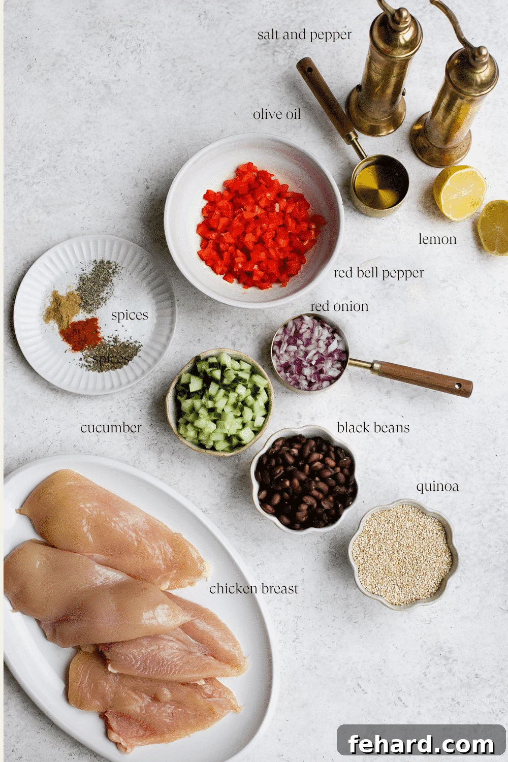 Ingredients laid out for chicken quinoa salad, including chicken, quinoa, vegetables, and dressing components.