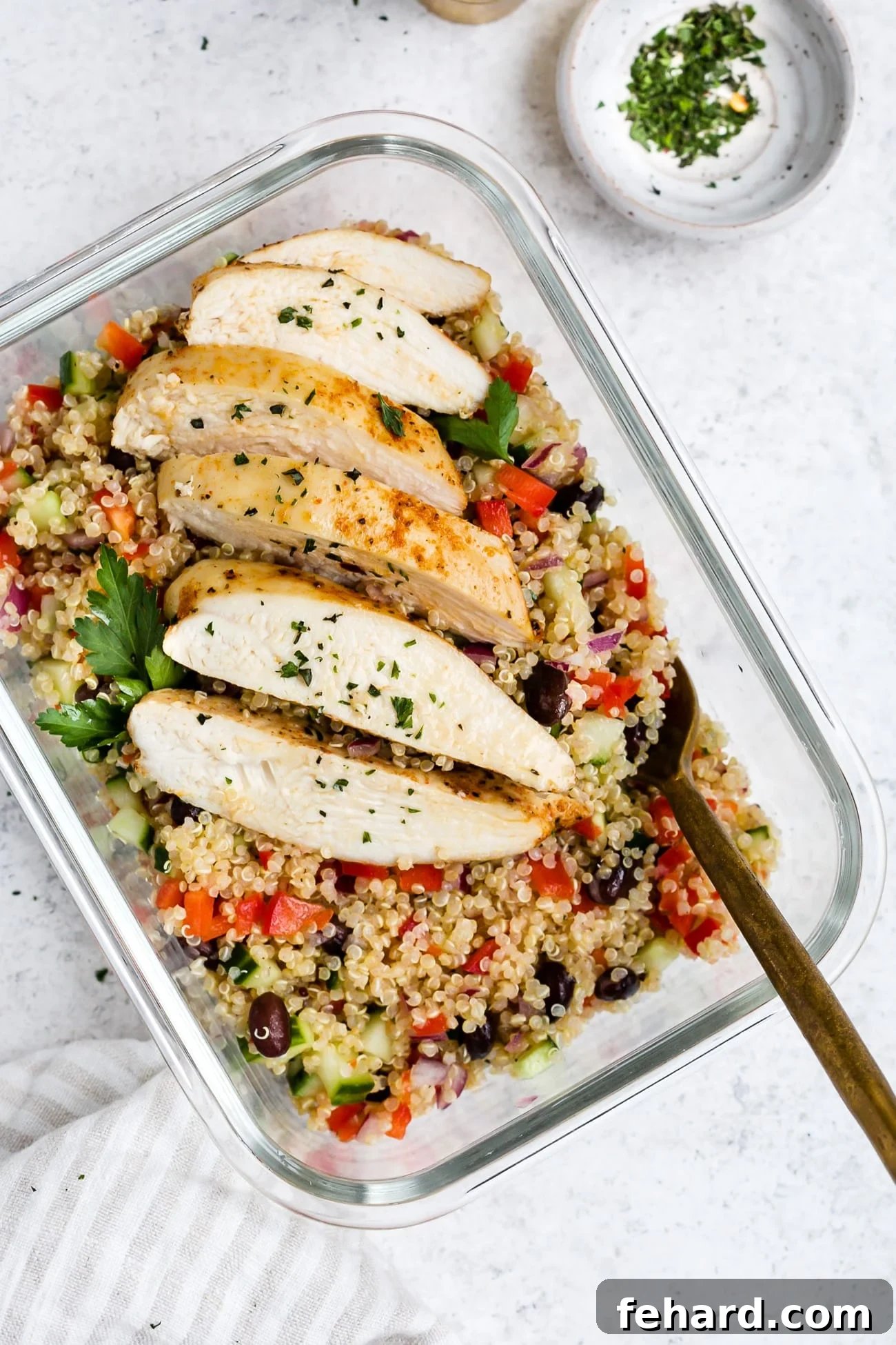 Chicken quinoa salad portioned into glass meal prep containers.