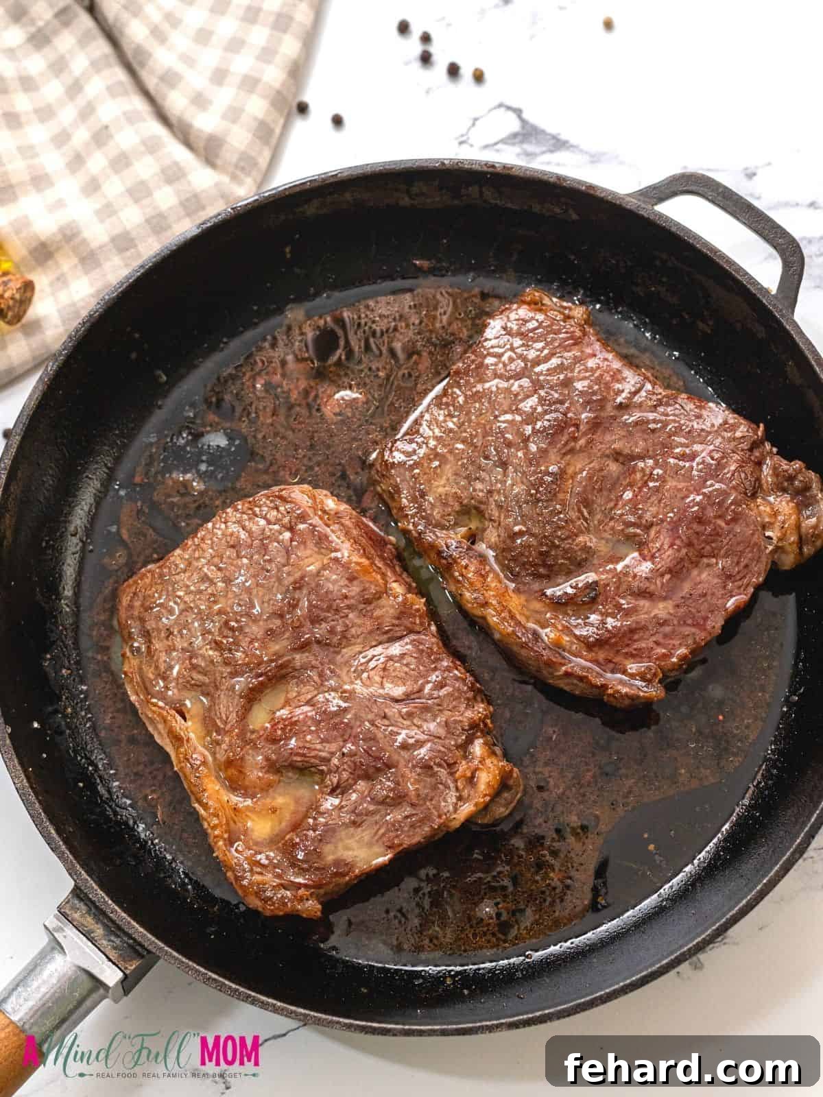 Two perfectly cooked ribeye steaks, one whole and one expertly sliced, revealing a vibrant red-pink center, resting on a wooden cutting board, ready to be served. The rich juices are visible, promising a tender and flavorful experience.