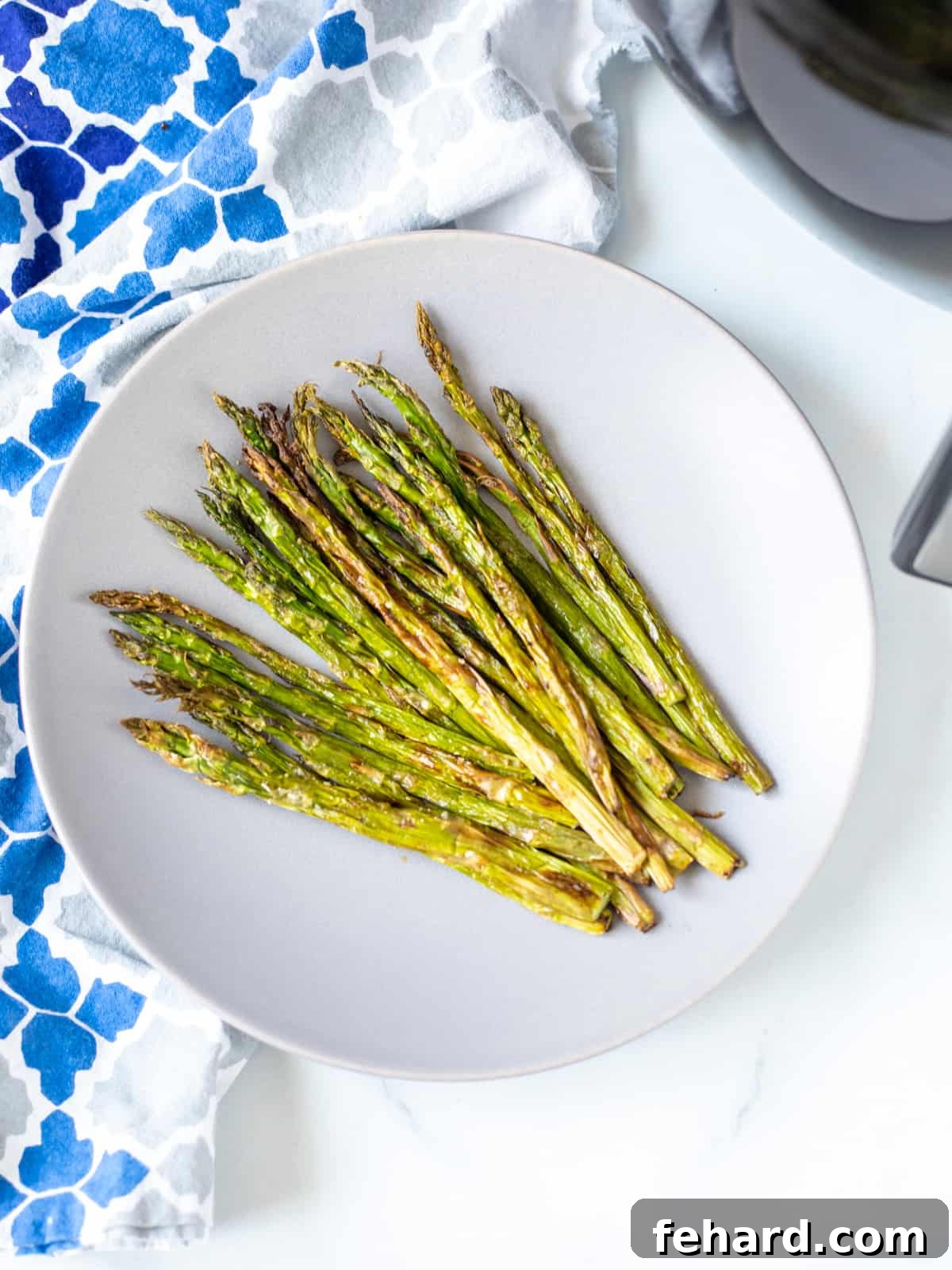 A vibrant plate of perfectly air-fried crispy asparagus, golden brown and seasoned, ready to serve.