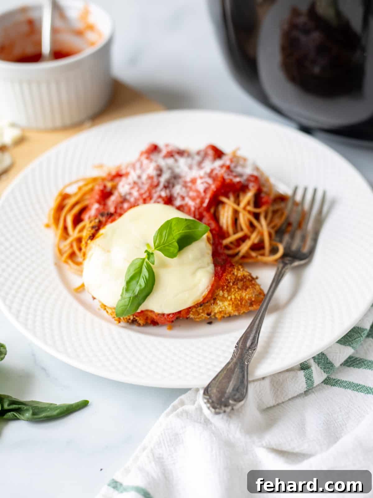 Air Fryer Chicken Parmesan on white plate served with side of spaghetti.