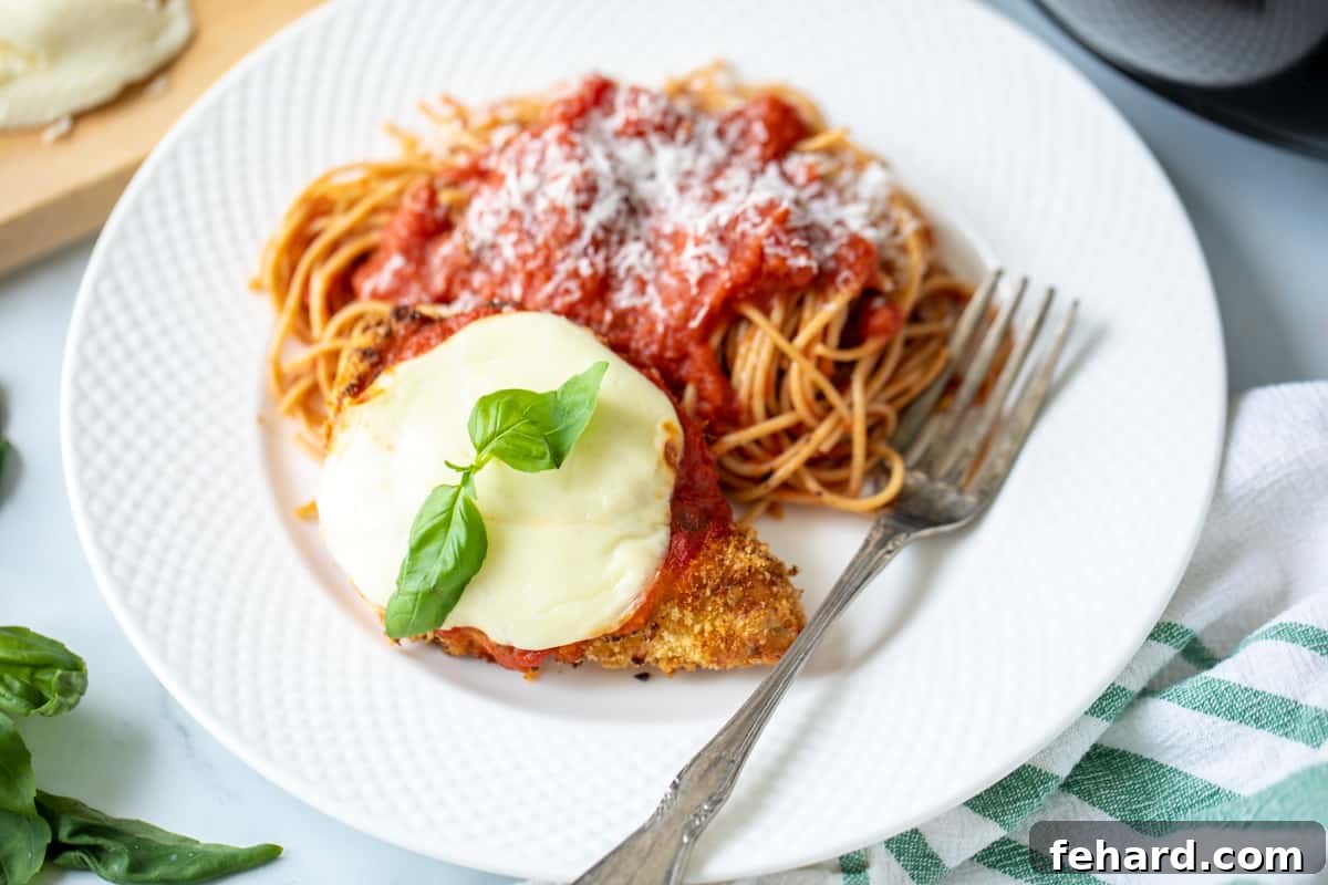Air Fryer Chicken Parmesan on a plate with a side of spaghetti.