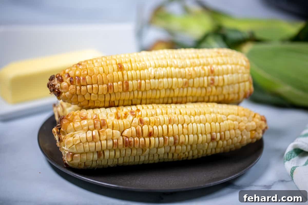 How to Make Corn in Air Fryer 3 ears of air fried corn on a black plate.