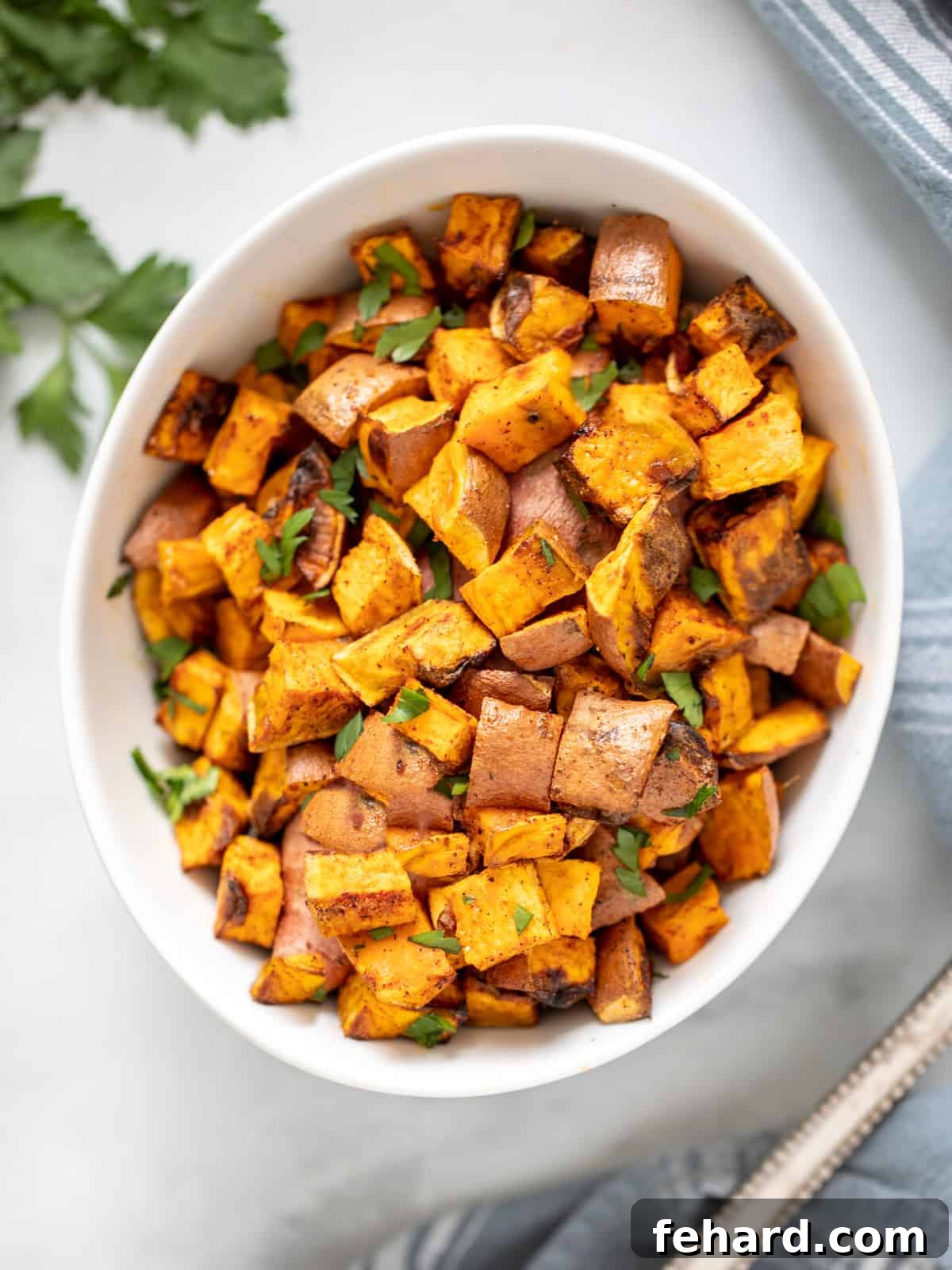 Bowl of crispy sweet potato cubes next to serving spoon.