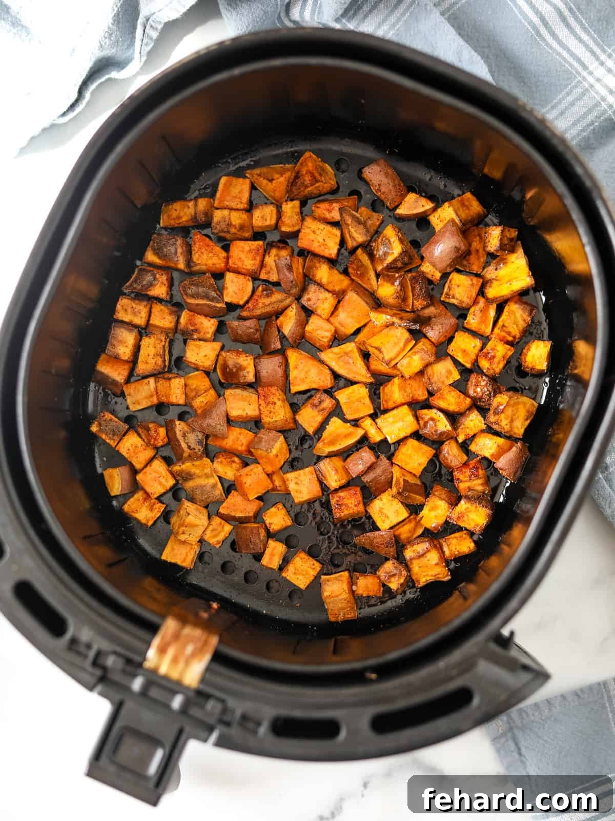Air Fryer Basket with cubed roasted sweet potatoes.