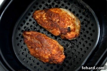 Air Fried Chicken breast with spice rub in air fryer basket after being flipped.