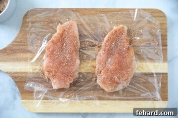 Chicken breasts pounded to even thickness and seasoned on plastic wrap.