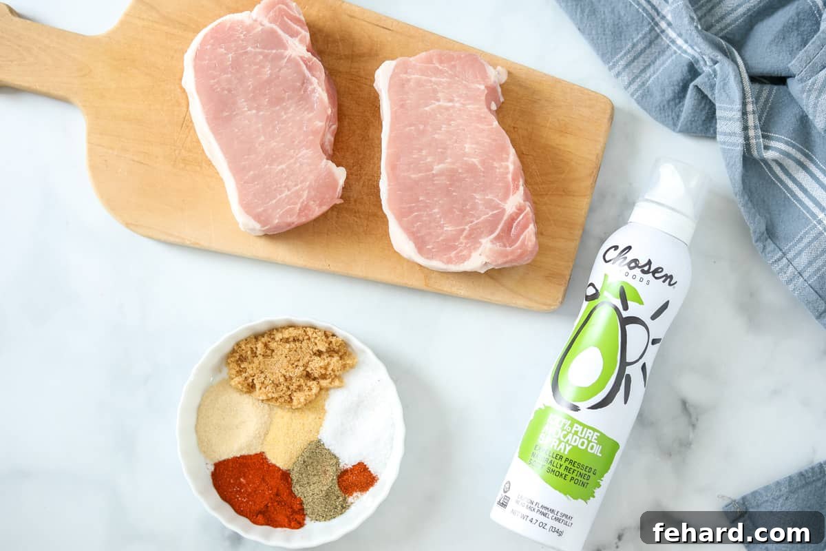 Pork chops, a bowl of spice rub, and cooking spray laid out on a kitchen counter, ready for preparation.