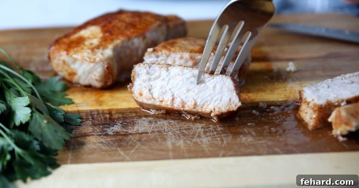 Perfectly sliced air fryer pork chops on a cutting board, a fork lifting a piece, showcasing the tender interior.