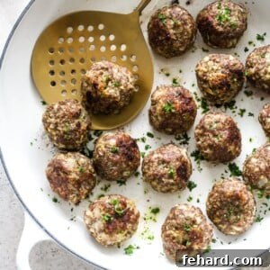 Overhead view of Turkey meatball in a white skillet, garnished with fresh herbs.