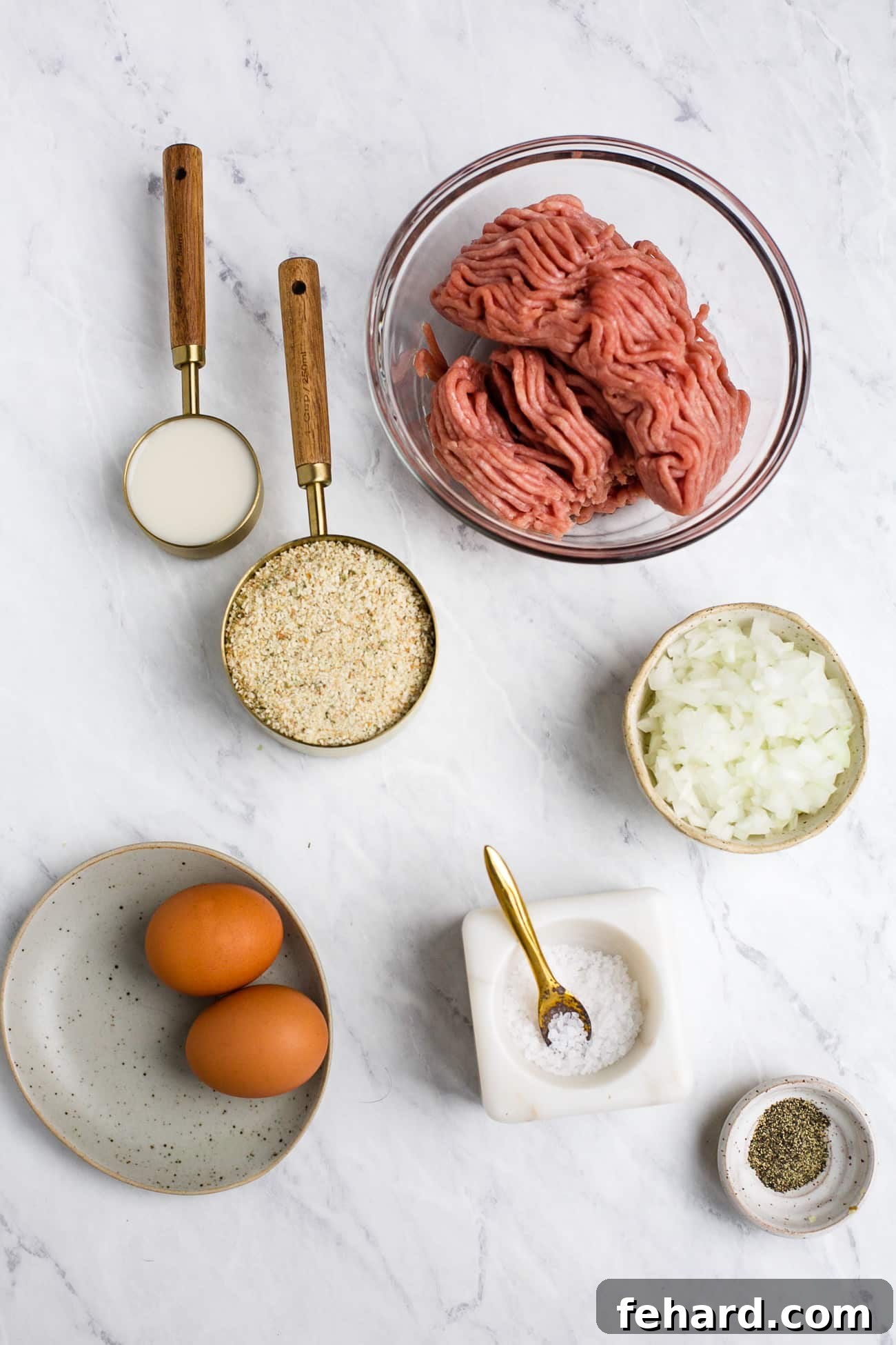 Ground turkey meatball ingredients laid out on a white surface.