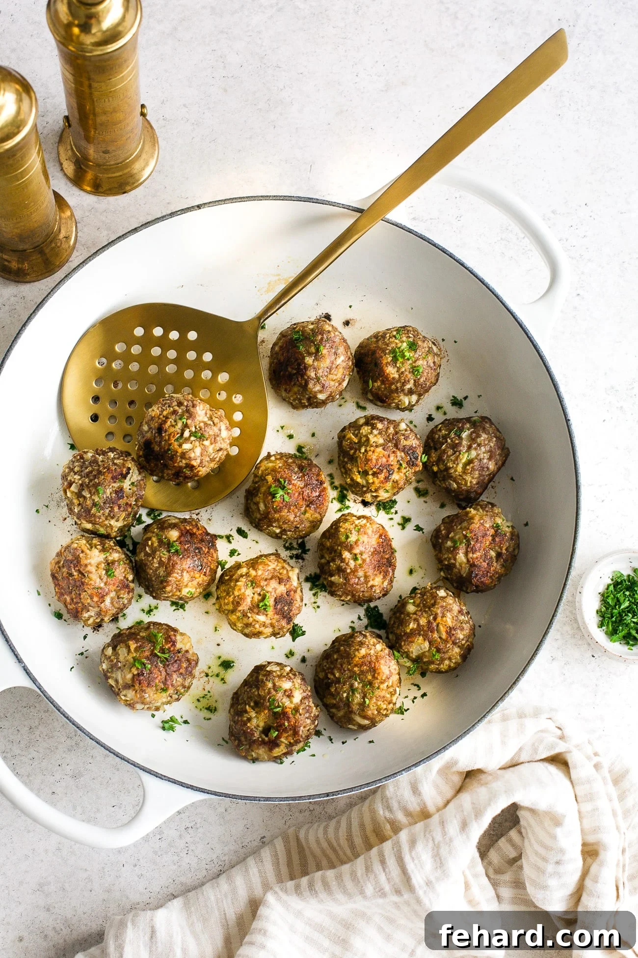Overhead view of turkey Meatball in a white skillet, garnished with fresh herbs.