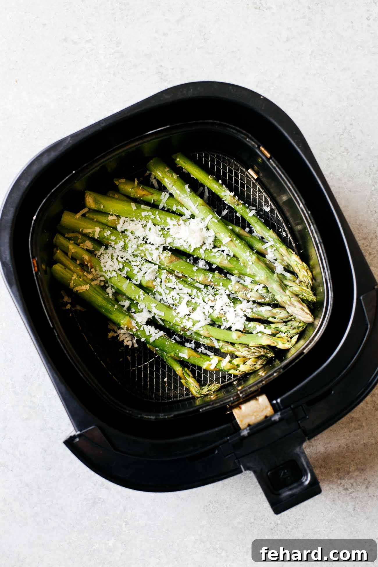 Asparagus spears evenly spread in a single layer inside an air fryer basket, ready to be cooked to crispy perfection.