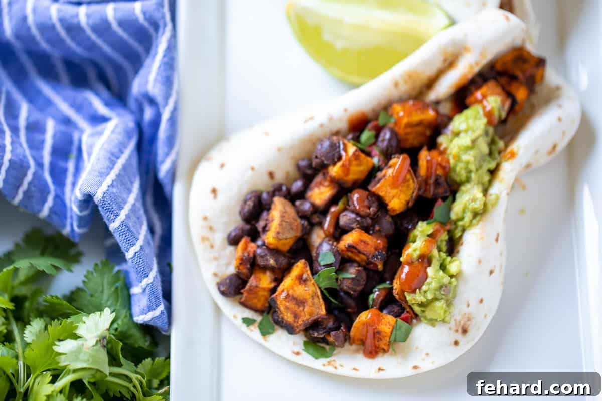 A single flour tortilla, perfectly folded and generously filled with the savory sweet potato and black bean mixture, topped with creamy guacamole.