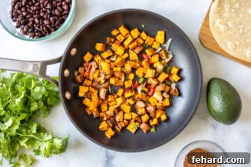 Sauteed cubed sweet potatoes in saute pan with peppers and onions next to black beans and taco seasoning.