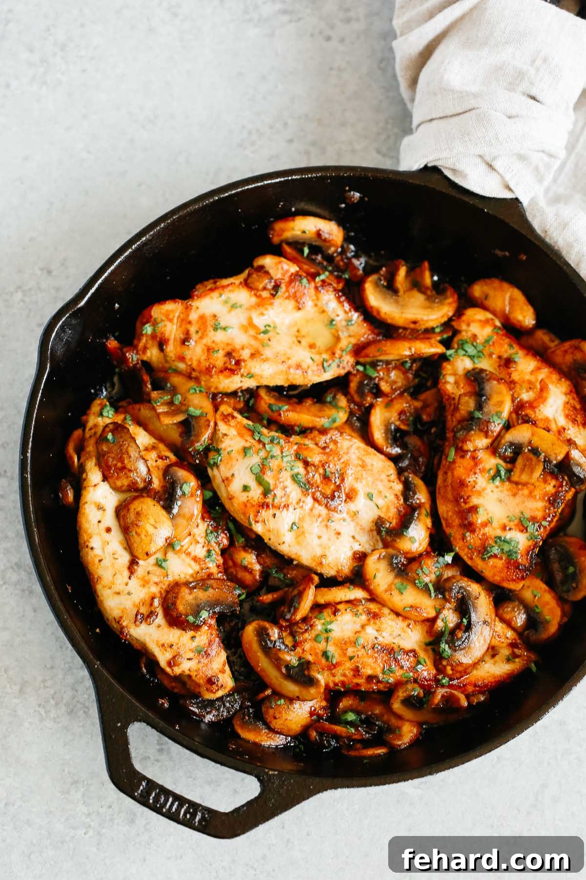 overhead photo of cooked chicken breasts and mushrooms in a cast iron skillet