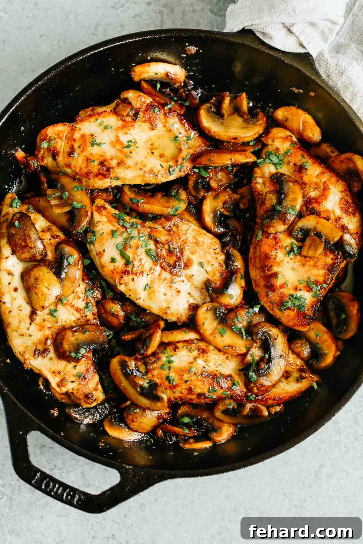 overhead photo of cooked chicken breasts and mushrooms in a cast iron skillet