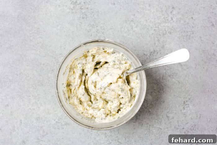 A small bowl filled with softened butter, minced garlic, salt, pepper, and fresh herbs, mixed to form the aromatic garlic butter rub.