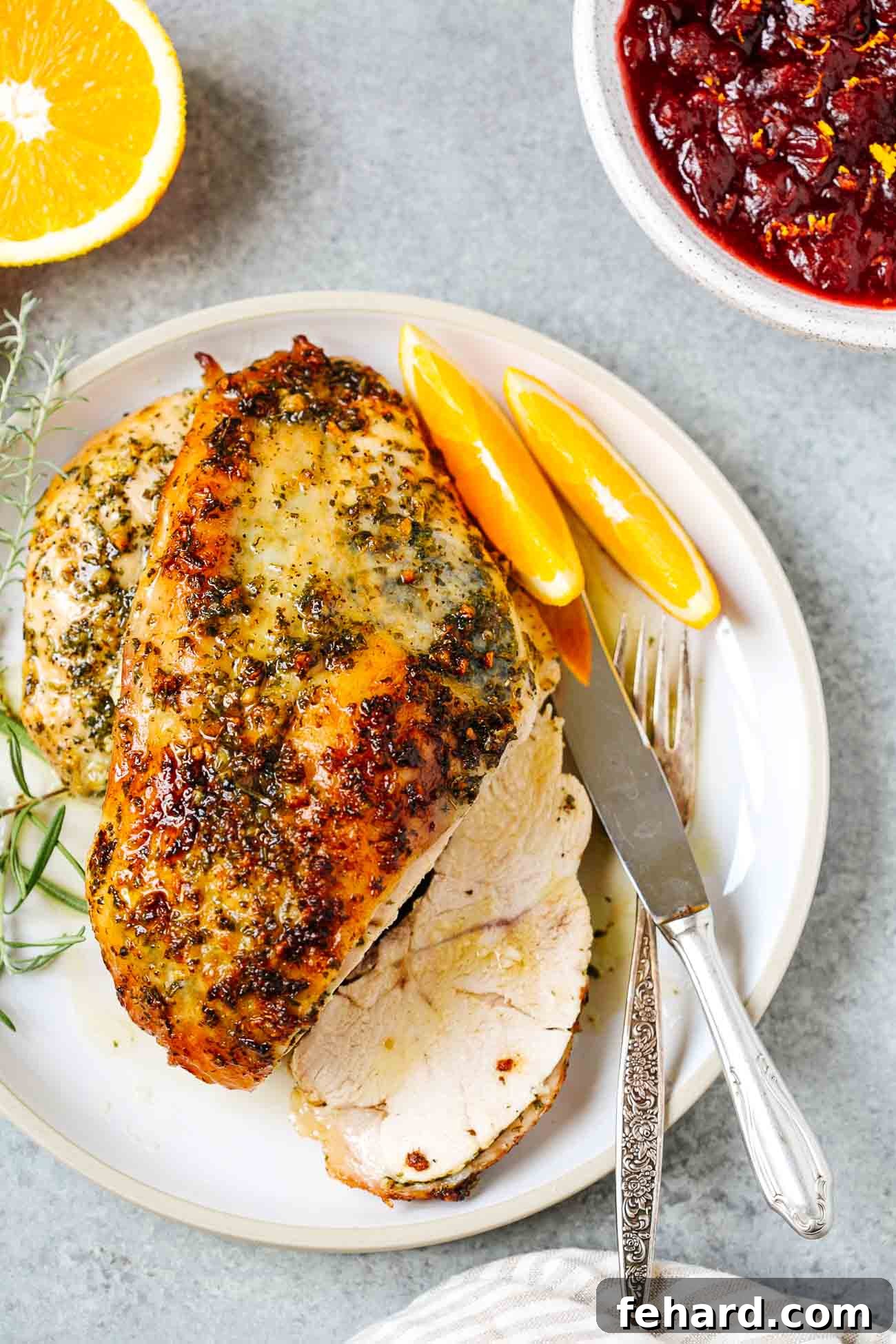 An overhead view of a perfectly roasted garlic butter turkey breast, carved into thick, juicy slices on a serving plate.