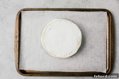 Brie cheese on a baking sheet, ready for the oven.