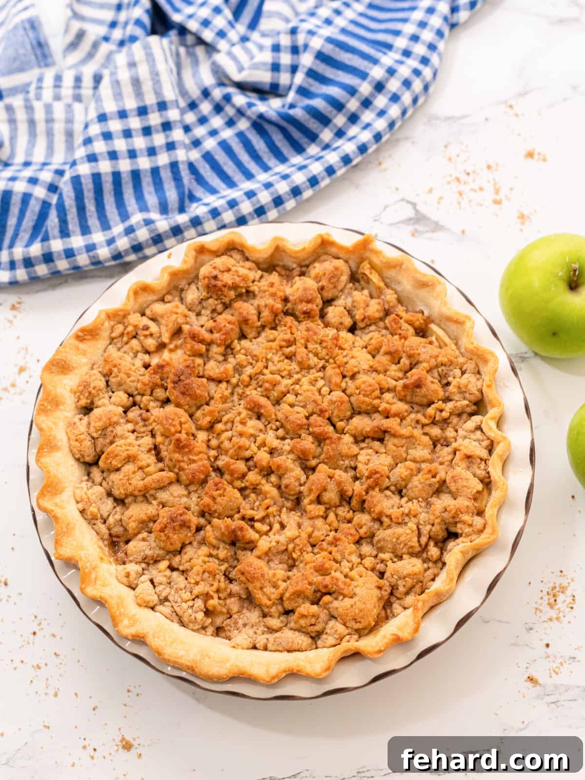 Perfectly Baked Dutch Apple Pie A freshly baked, golden brown Dutch Apple Pie sitting on a rustic wooden surface, with fresh Granny Smith apples scattered around it, highlighting its natural ingredients.