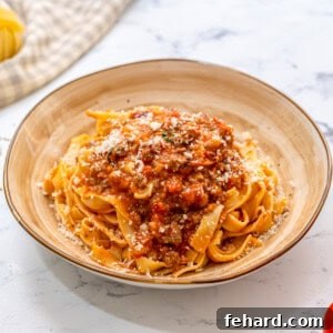 Pasta topped with rich bolognese sauce on a cream plate, ready to be enjoyed.