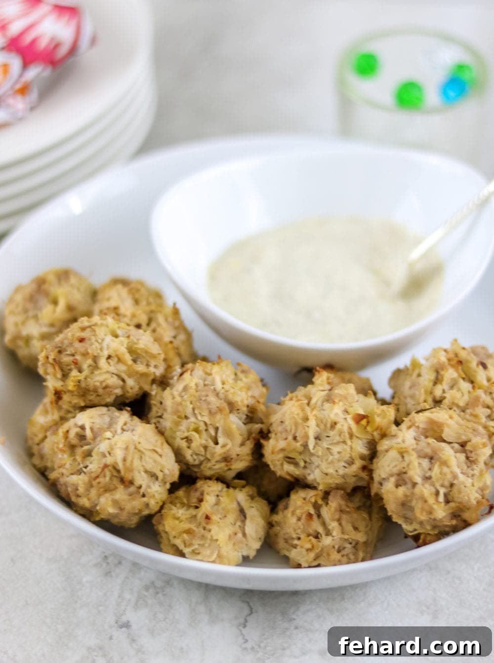Baked sauerkraut balls on white platter served with creamy dipping sauce.
