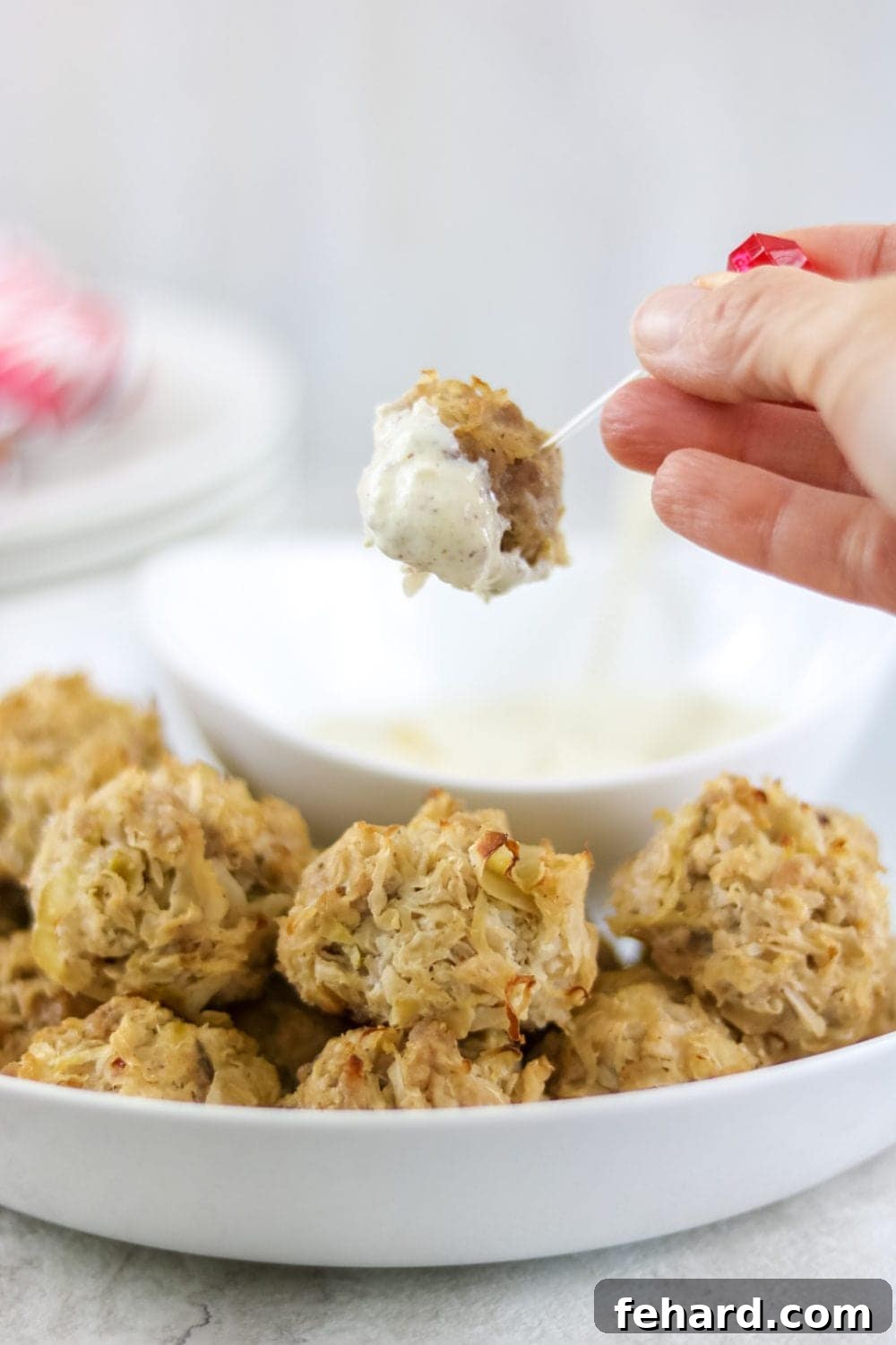 Baked sauerkraut ball being dipped into Creamy Horseradish mustard sauce