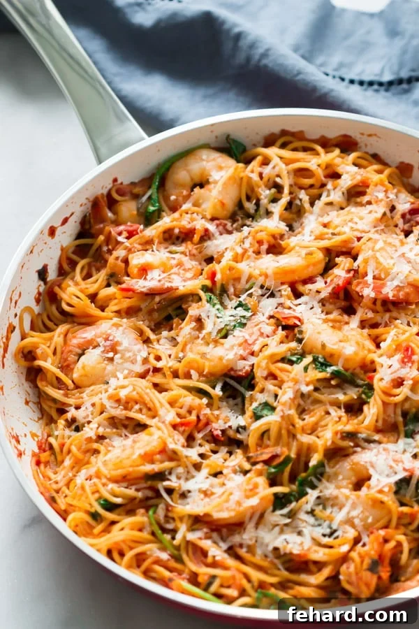 Overhead view of a white pan with perfectly cooked spaghetti and pink shrimp