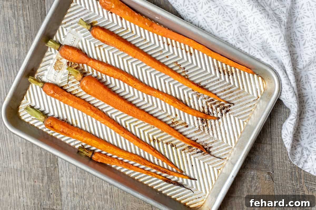 How to cook carrots Carrots evenly spread on a baking sheet, drizzled with olive oil and sprinkled with salt and pepper, ready for roasting.