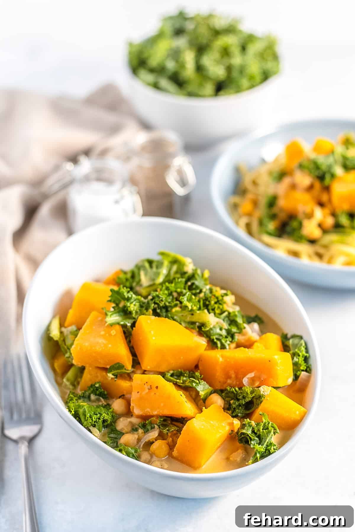 A vibrant bowl of vegetarian butternut squash curry with chickpeas and fresh kale, ready to be enjoyed.