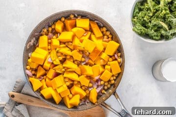Saucepan with squash and chickpeas submerged in a flavorful broth, ready to simmer.