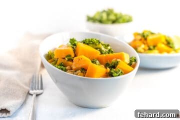 A beautifully presented white bowl overflowing with vegan butternut squash curry.