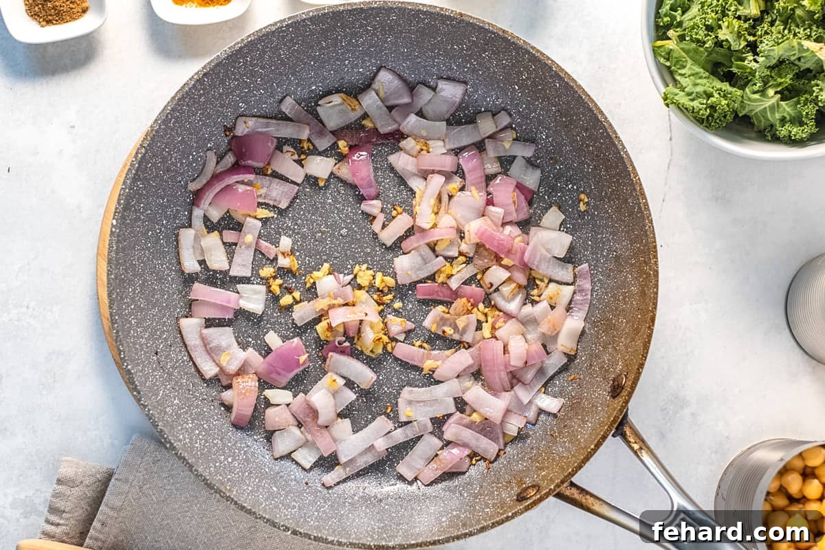 Finely diced onions and freshly grated ginger are gently sautéing in a saucepan, releasing their aromatic flavors.