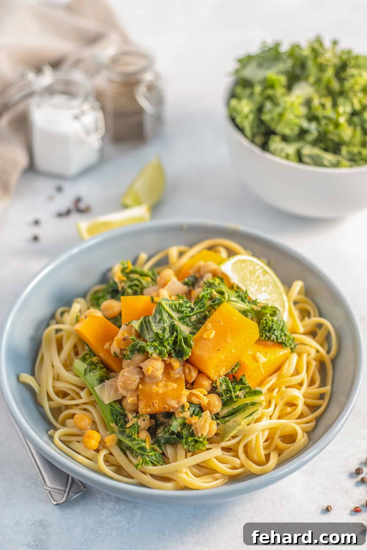 A beautifully plated bowl of butternut squash and chickpea curry served over al dente pasta, garnished with fresh cilantro.