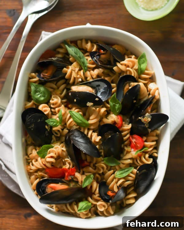 Whole Wheat Fusilli with Mussels Whole Wheat Fusilli with Mussels and cherry tomatoes in a white baking dish, garnished with fresh basil.