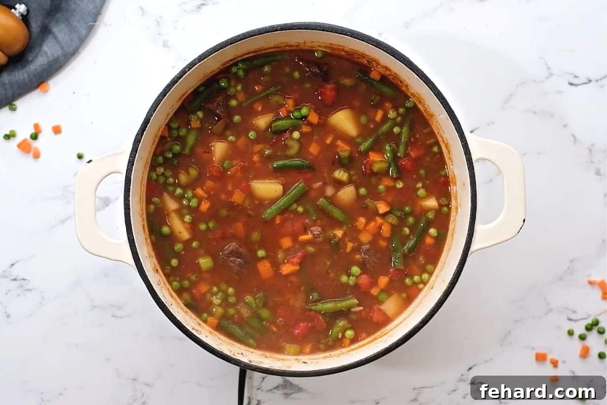 Vegetable Beef Soup in a large Dutch oven, showcasing potatoes, green beans, carrots, and peas cooked to perfection.