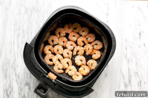 overhead view of basket air fryer containing cooked shrimp