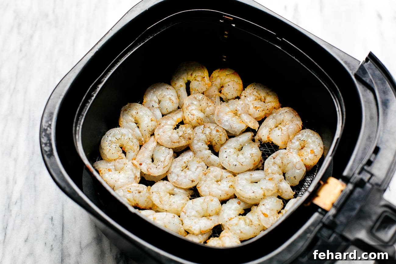 Crispy Air Fried Shrimp 4 Overhead view of raw seasoned shrimp arranged in a single layer inside an air fryer basket, ready for cooking.