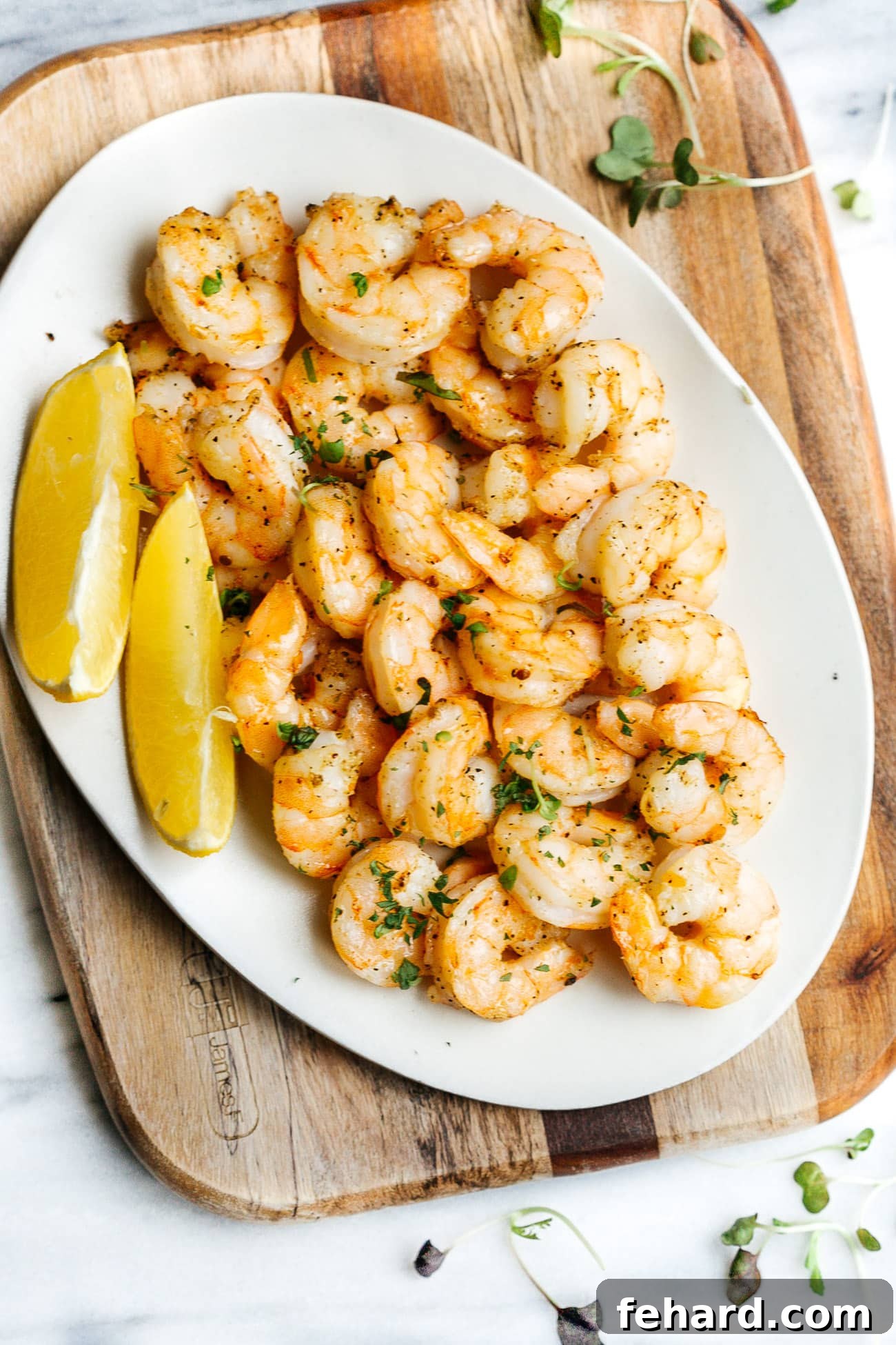 Crispy Air Fried Shrimp 6 A beautifully presented white plate filled with cooked air fryer shrimp, garnished with fresh herbs and a slice of lemon, ready for serving.