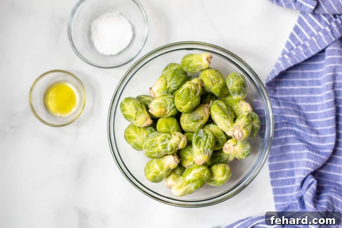 Bowl of Brussels Sprouts next to olive oil and salt. 