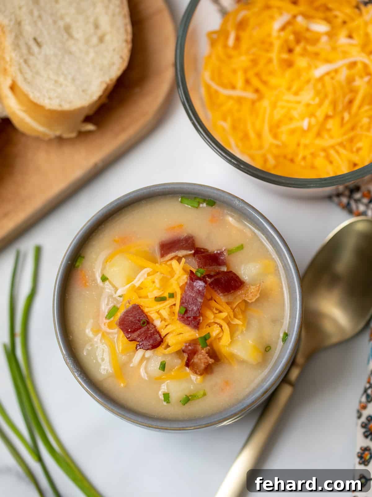 Healthy Potato Soup Recipe A steaming bowl of creamy potato soup, generously topped with shredded cheese and crispy bacon bits, served alongside fresh sliced bread.