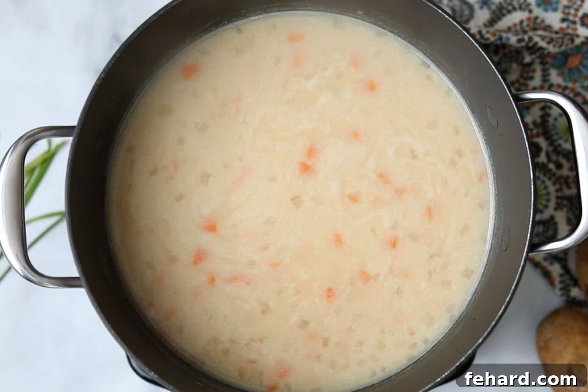 Loaded Baked Potato Soup Base The creamy potato soup simmering gently in a saucepan on the stove, having reached its perfect consistency.