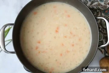 Creamy potato soup simmering in a saucepan on the stove.