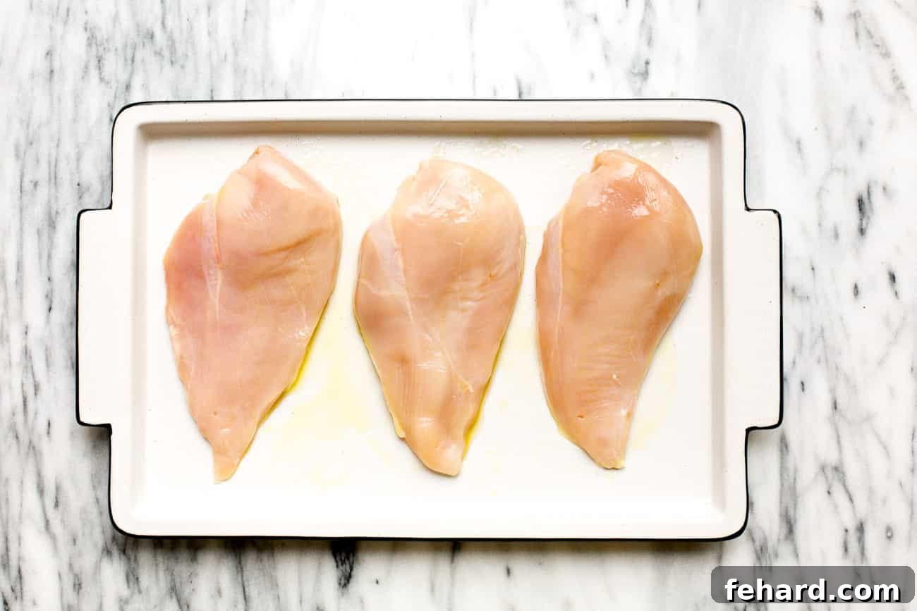 overhead view of raw chicken breast on a baking sheet